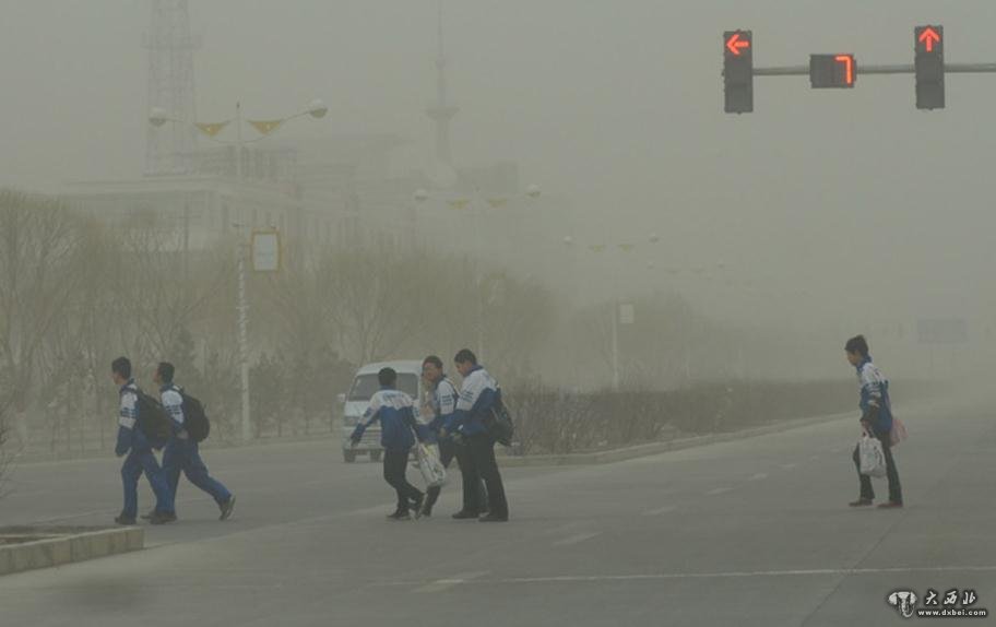 图为玉门市民在沙尘暴天气艰难出行。