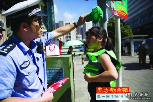  昨日，罗湖区一十字路口一女子闯红灯被抓，很配合地穿上绿马甲戴上绿帽子。南都记者 陈文才 摄